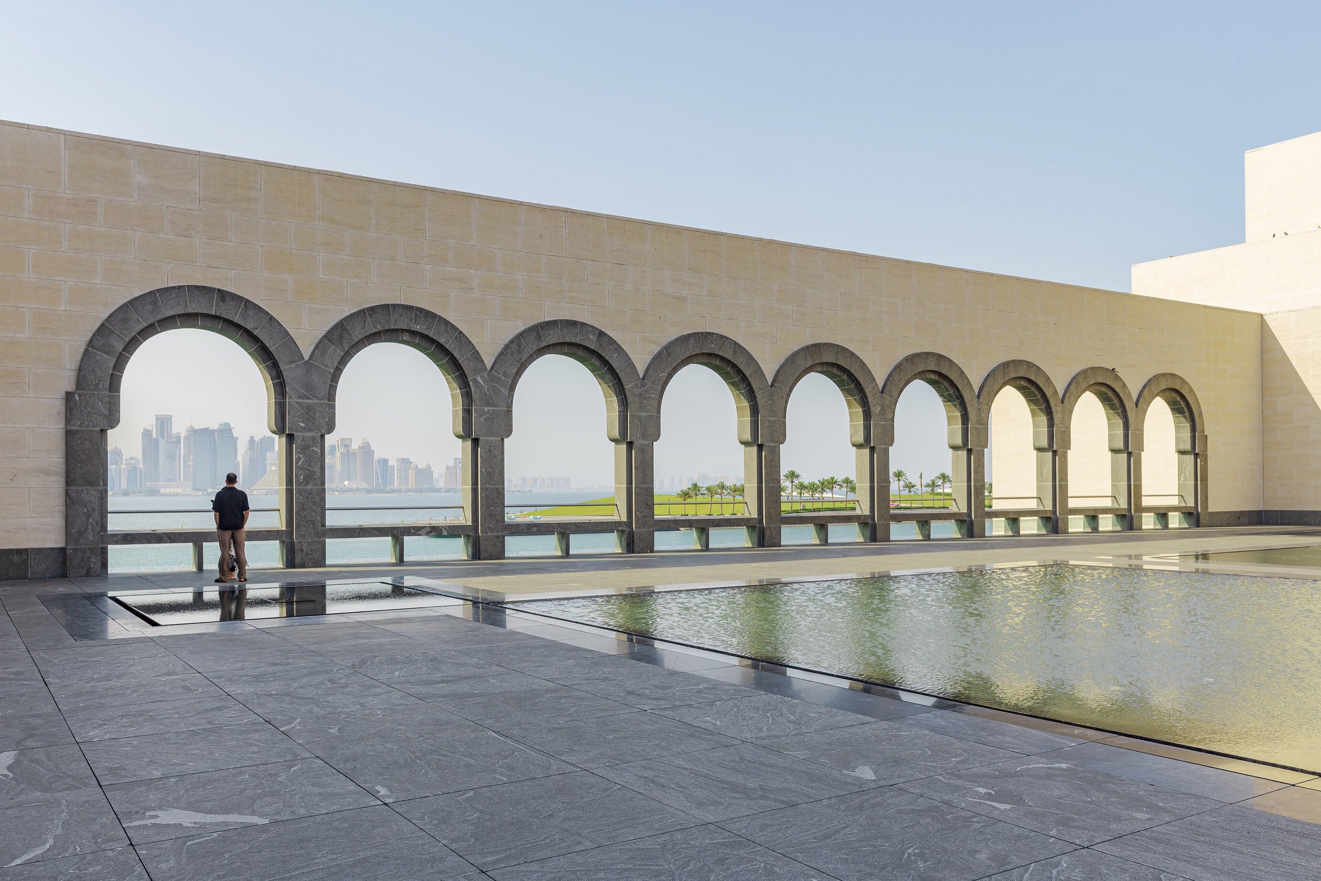 Arched courtyard of the Museum of Islamic Art in Doha with the city skyline beyond