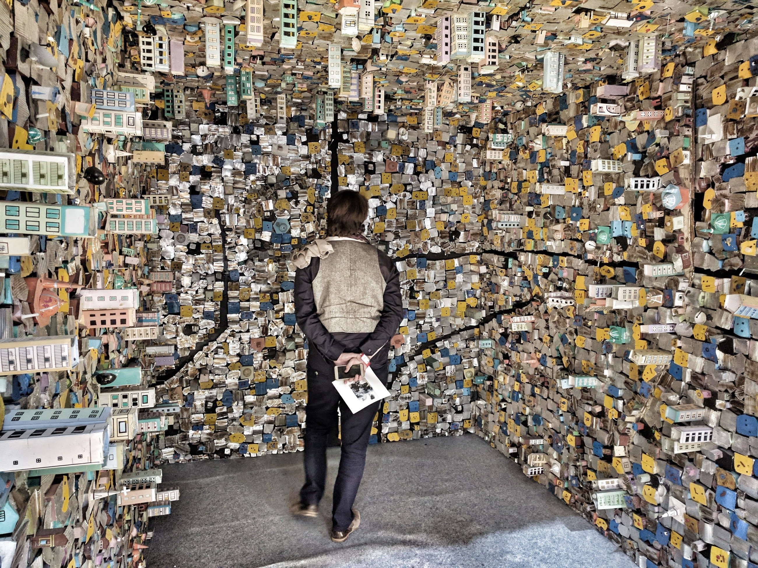 Visitor inside an immersive installation covered in miniature painted houses at India Art Fair